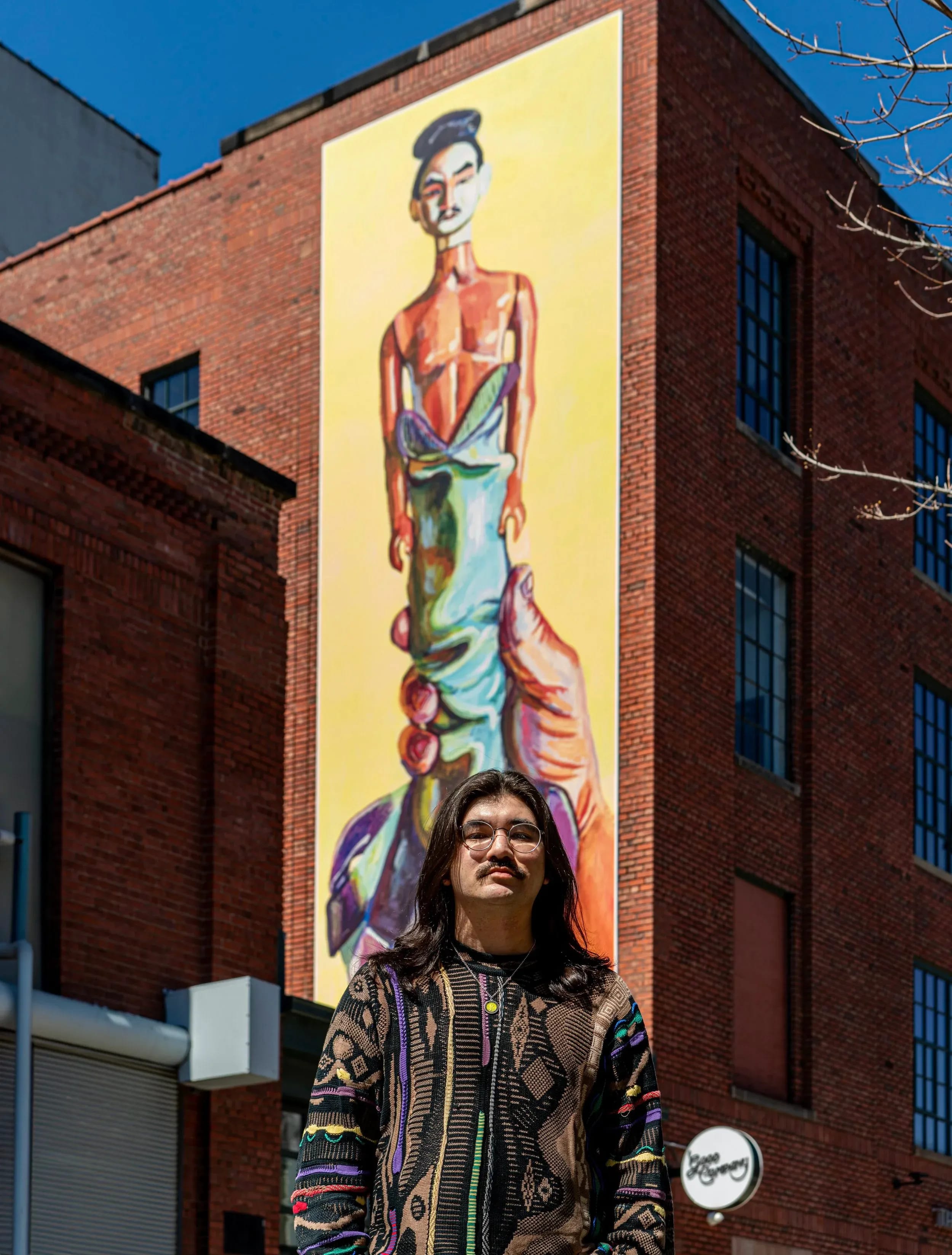Nick Lee posed in front of his mural titled This Yokai is a Ningyo.