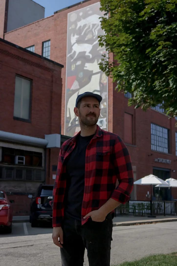 Jon Kvassay posed in front of his mural aptly titled Mural. Photo by Lex Cuevas.